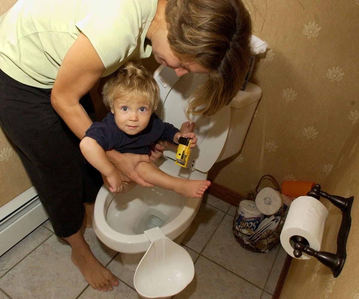 A mother holding her son over a toilet, related to EC