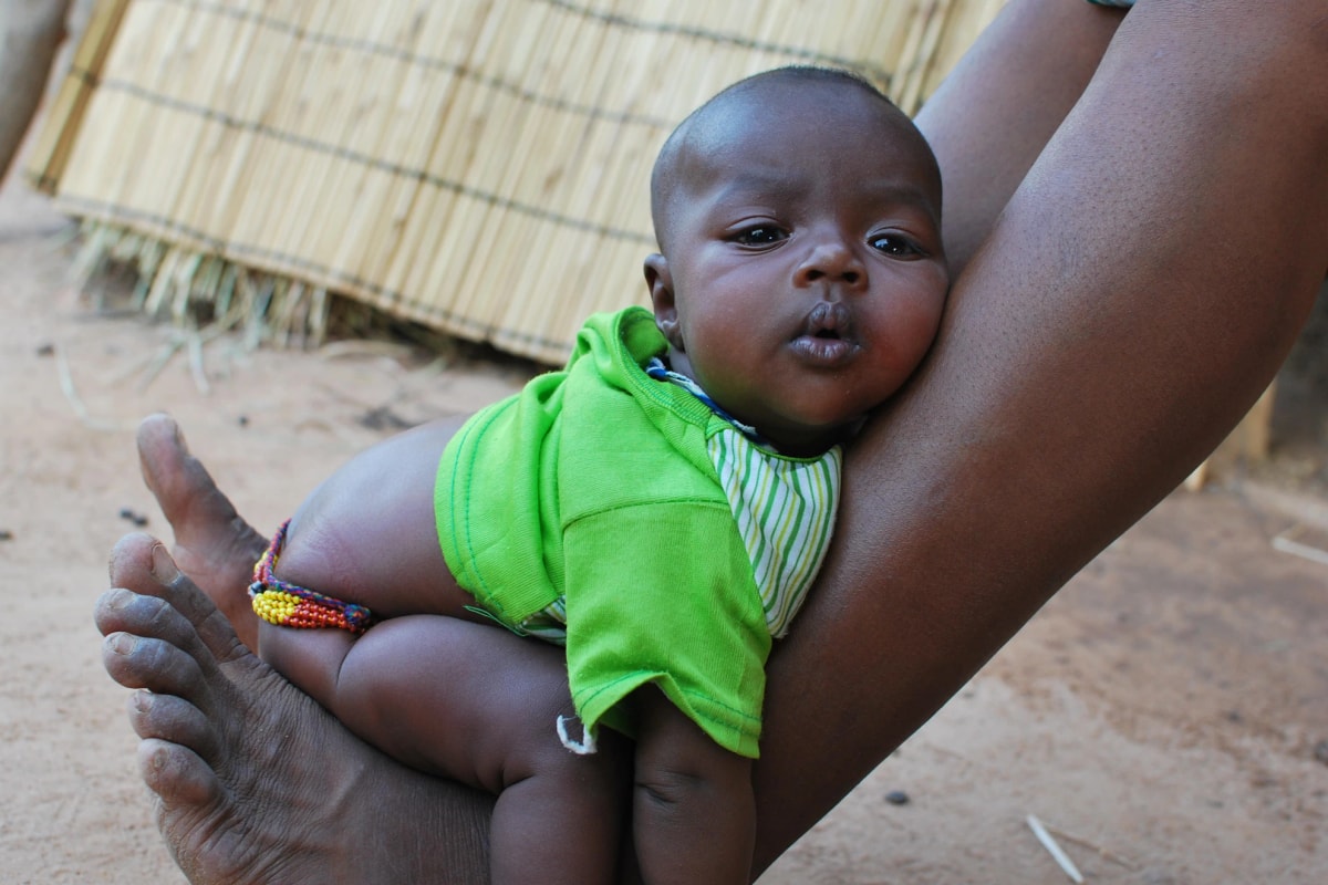 Infant potty training in Africa, a baby sitting on a carers ankles