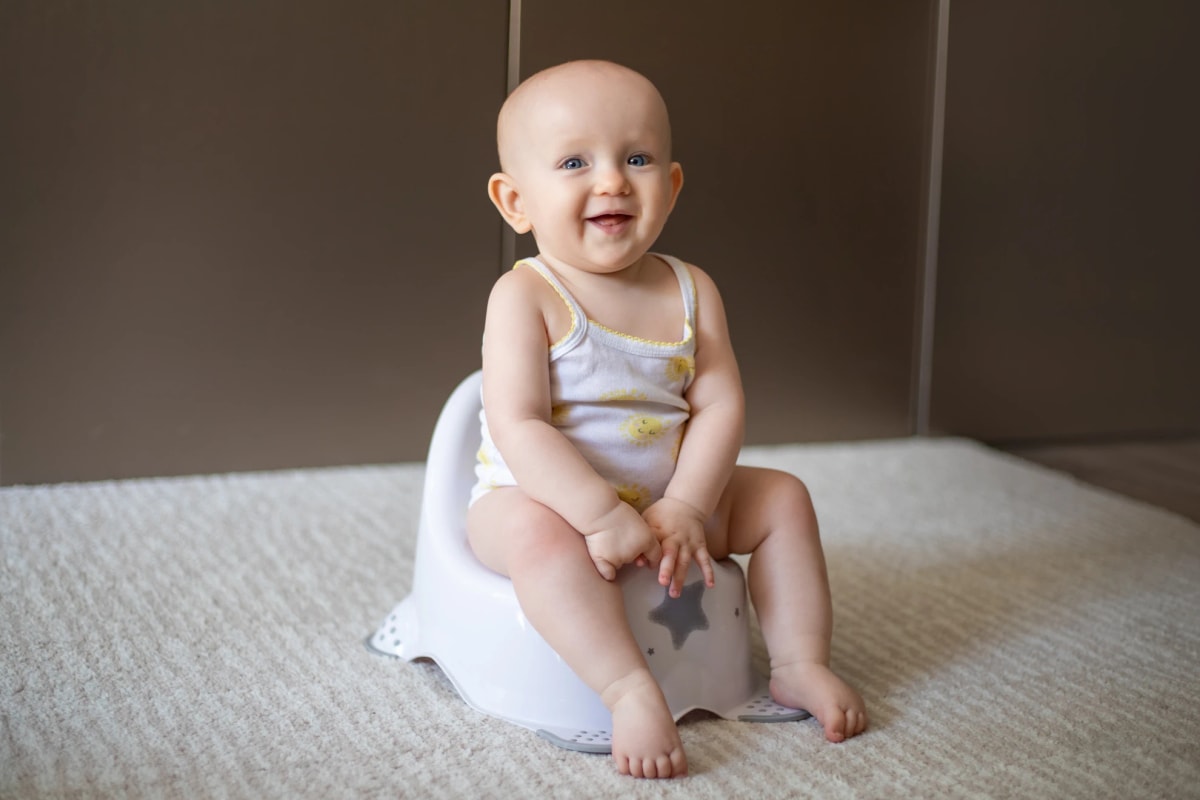 A happy six months old baby sitting on a pottry