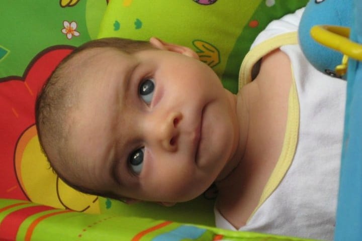 A 3 month old baby lying on an activity mat