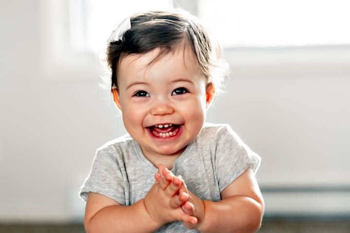 A nine month old baby clapping and smiling