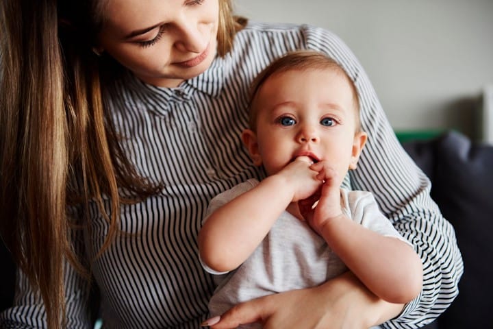 A baby sitting on thir mothers lap